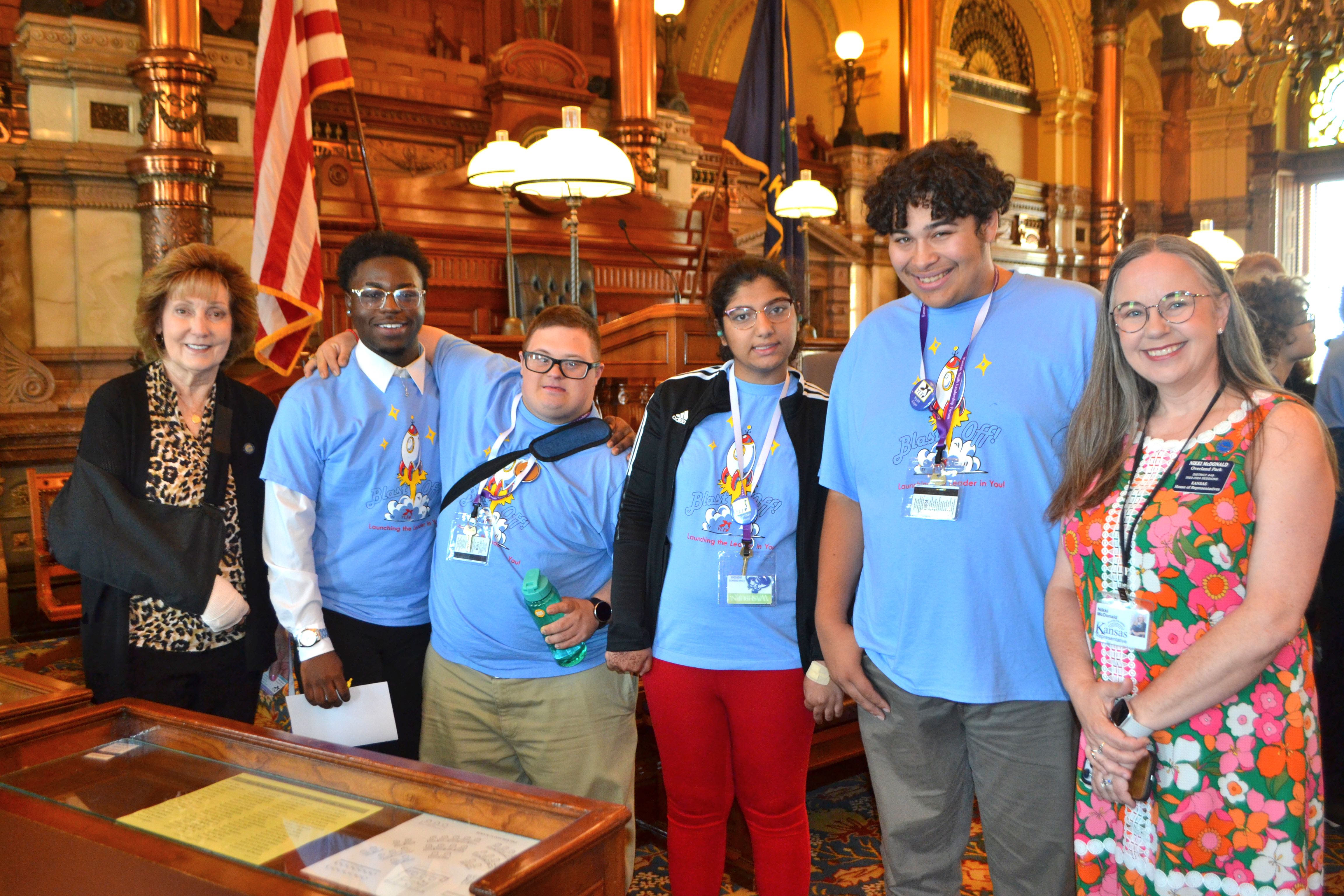 Four delegates taking a photo with 2 legislators in the Senate Chambers